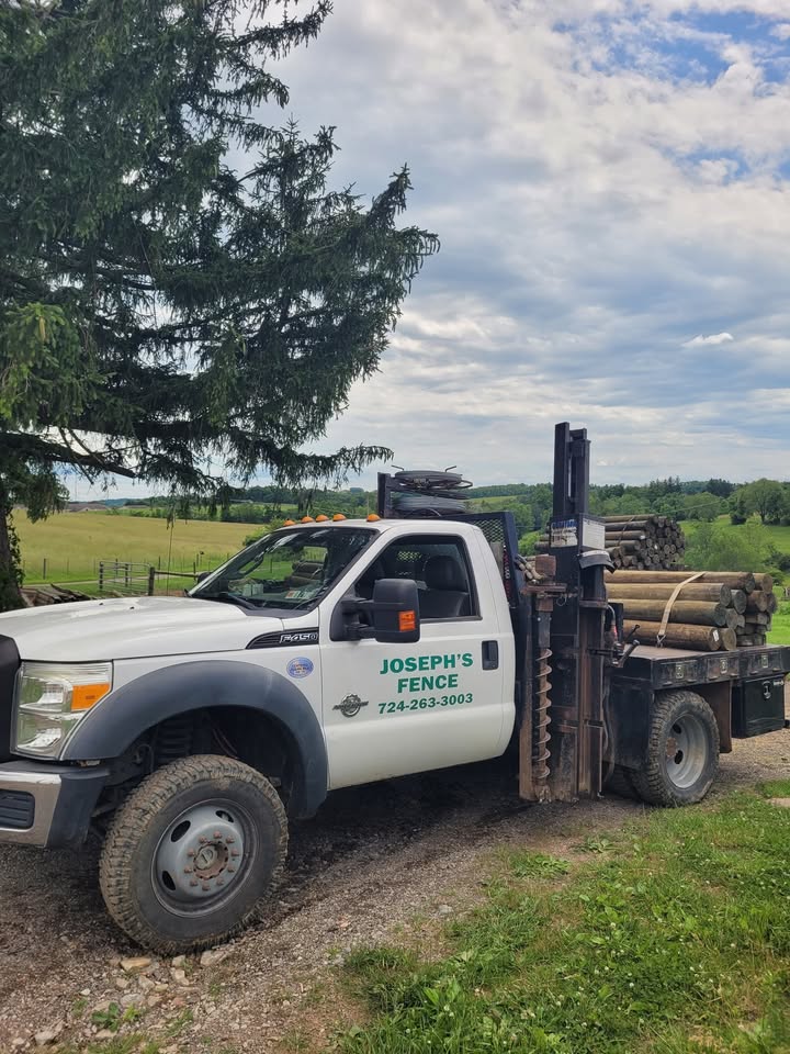 Joseph's Fence work truck loaded with fence posts and a post-hole auger